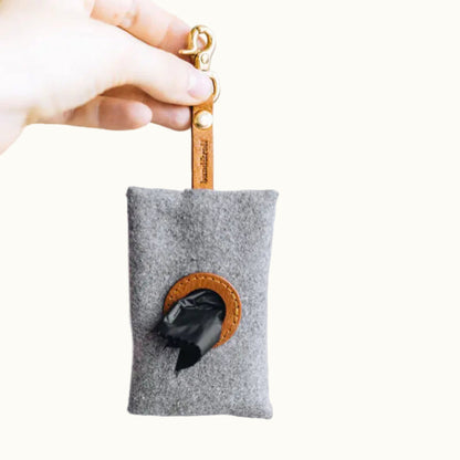 Gray felt pouch with black interior and brown Faux leather accents held by a hand against a white background